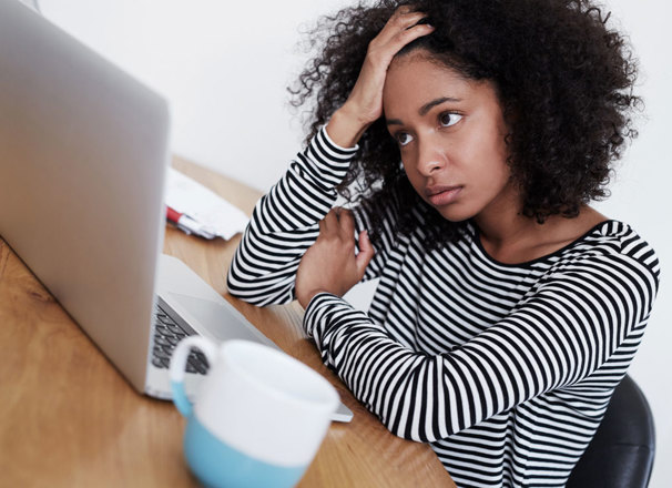 Frustrated person holding head in hand looking at computer