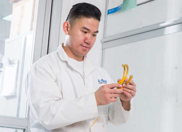 Person wearing a lab coat inspecting a tool