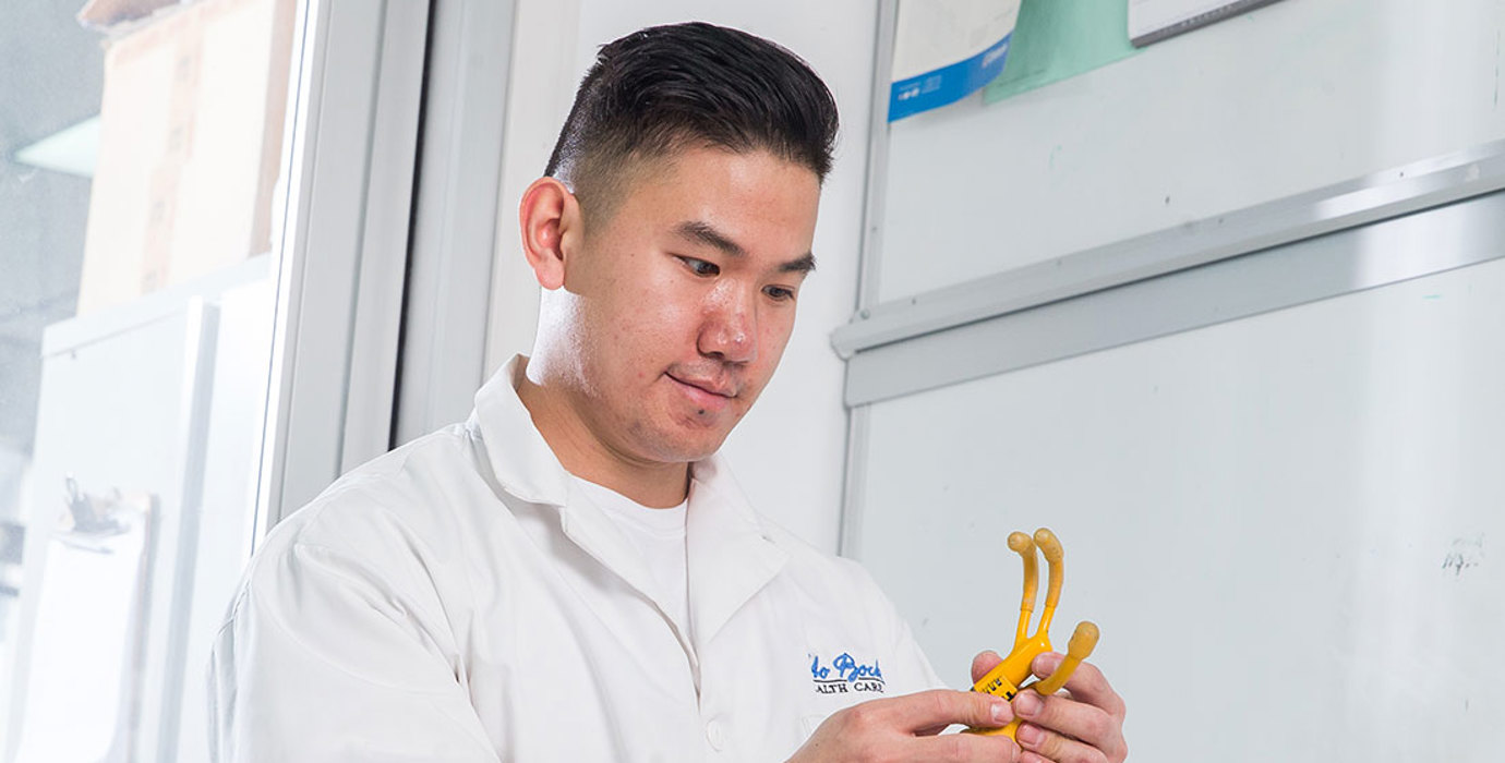 Person wearing a lab coat inspecting a tool