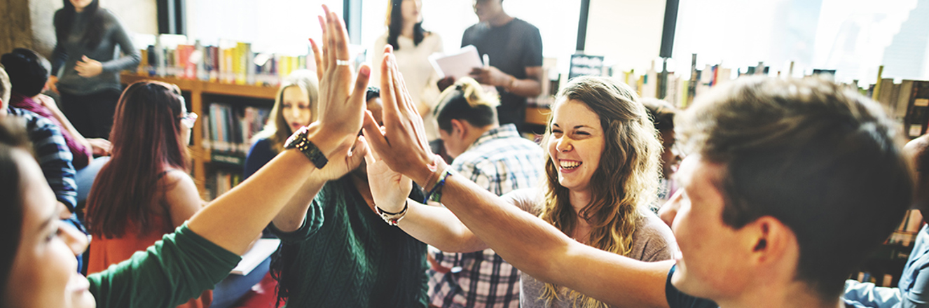 Students high fiving in a library