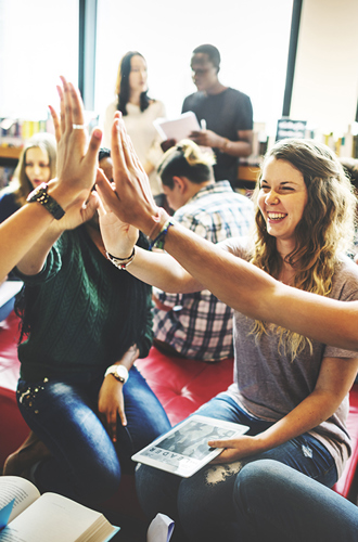 Students high fiving in a library