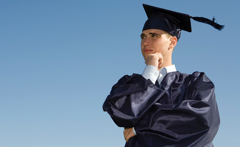 New graduate wearing cap and gown with hand on chin