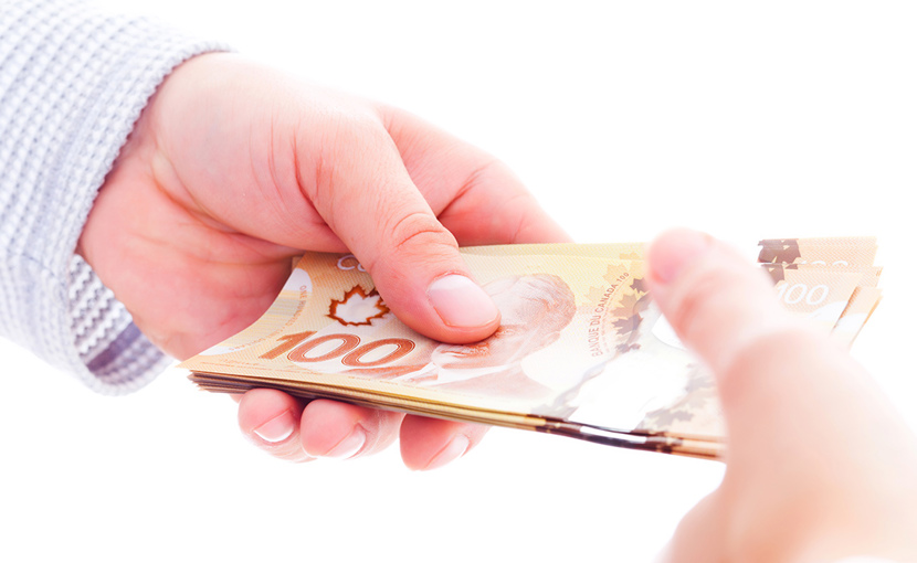 Hands exchanging Canadian hundred dollar bills