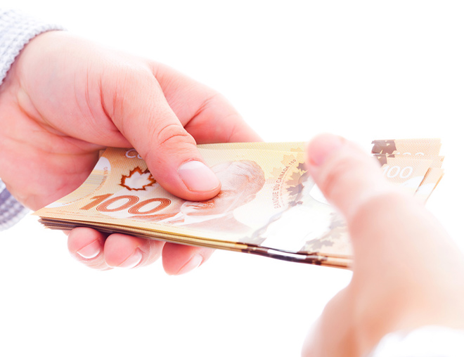 Hands exchanging Canadian hundred dollar bills