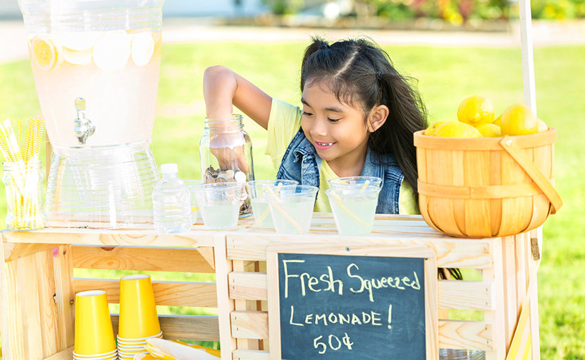 Youth picking coins out of a jar at a lemonade stand