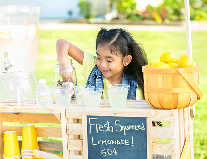 Youth picking coins out of a jar at a lemonade stand