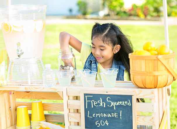 Youth picking coins out of a jar at a lemonade stand