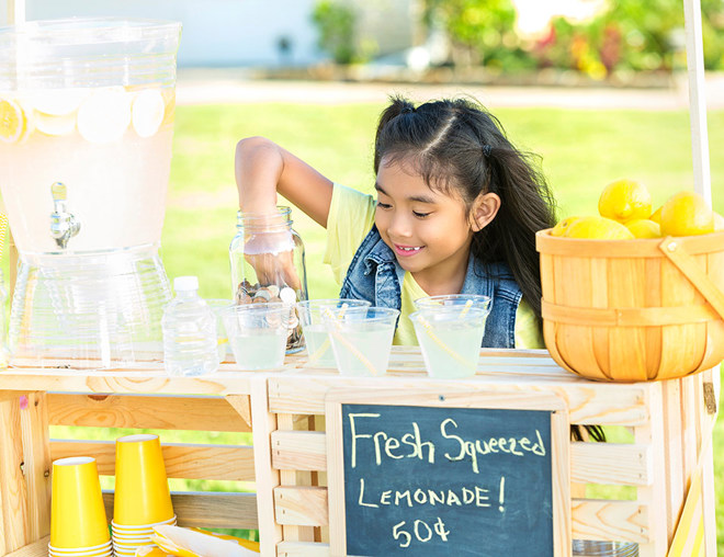 Youth picking coins out of a jar at a lemonade stand
