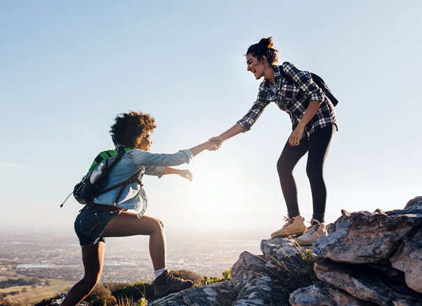 Friends helping each other climb up a hill