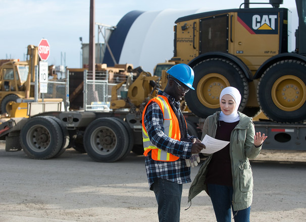 Employees on a jobsite having a discussion in front of large equipment