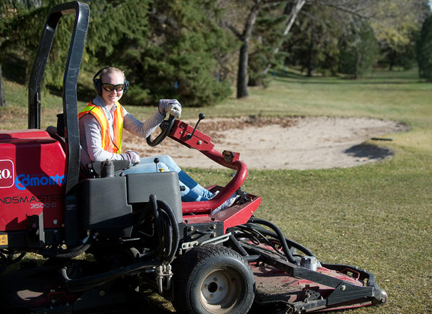 Golf course groundskeeper riding the mower
