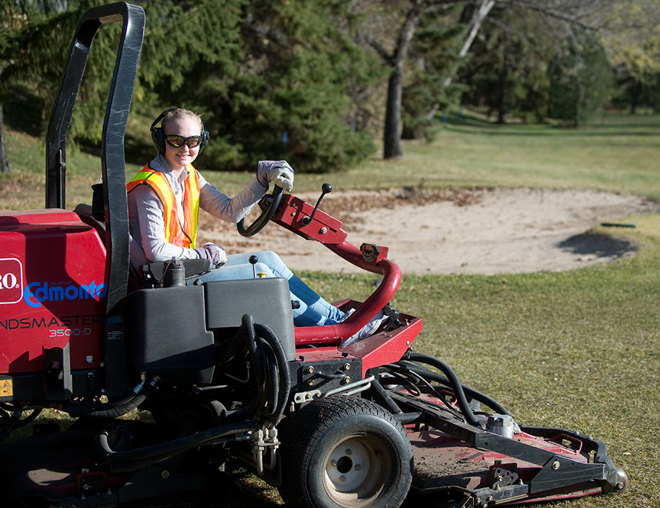 Golf course groundskeeper riding the mower
