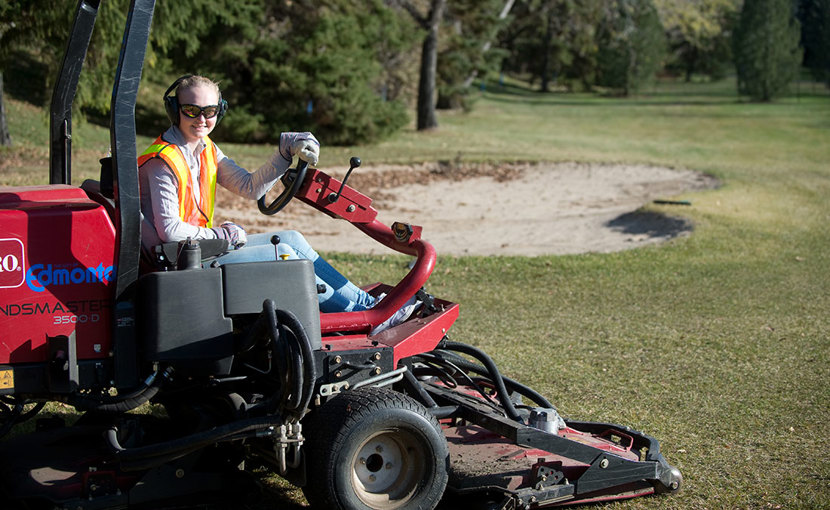 Golf course groundskeeper riding the mower