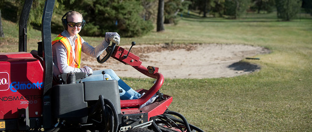 Golf course groundskeeper riding the mower