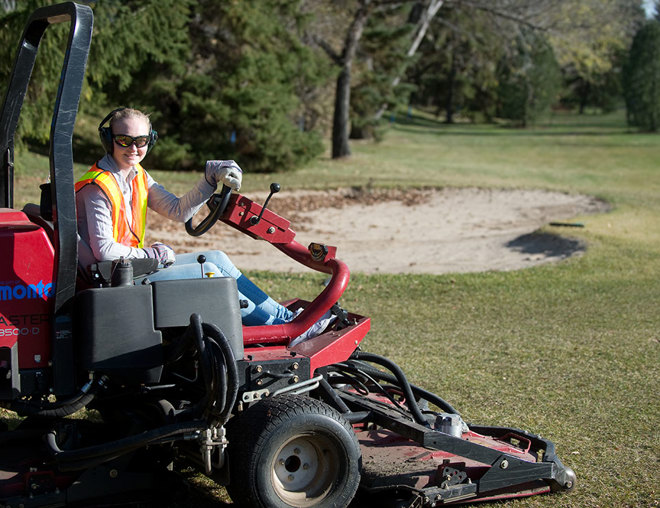 Golf course groundskeeper riding the mower