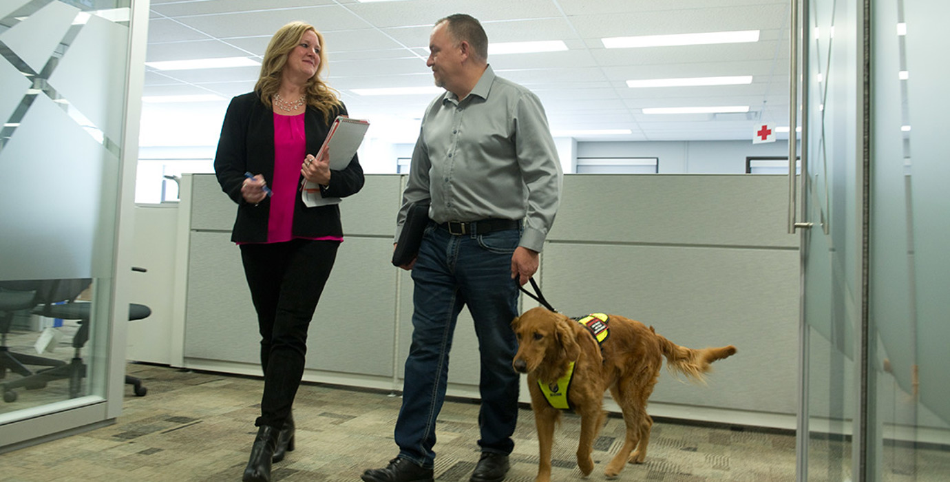 Employee with service dog talking with another employee in the office