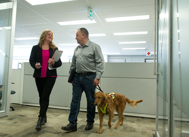 Employee with service dog talking with another employee in the office