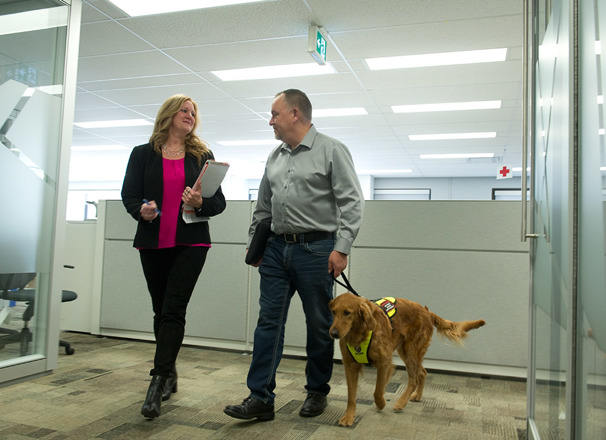 Employee with service dog talking with another employee in the office