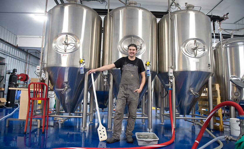 Entrepreneur in a brewer standing in front of fermenters