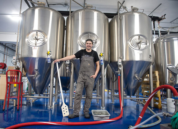 Entrepreneur in a brewer standing in front of fermenters