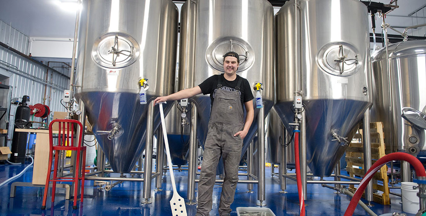 Entrepreneur in a brewer standing in front of fermenters