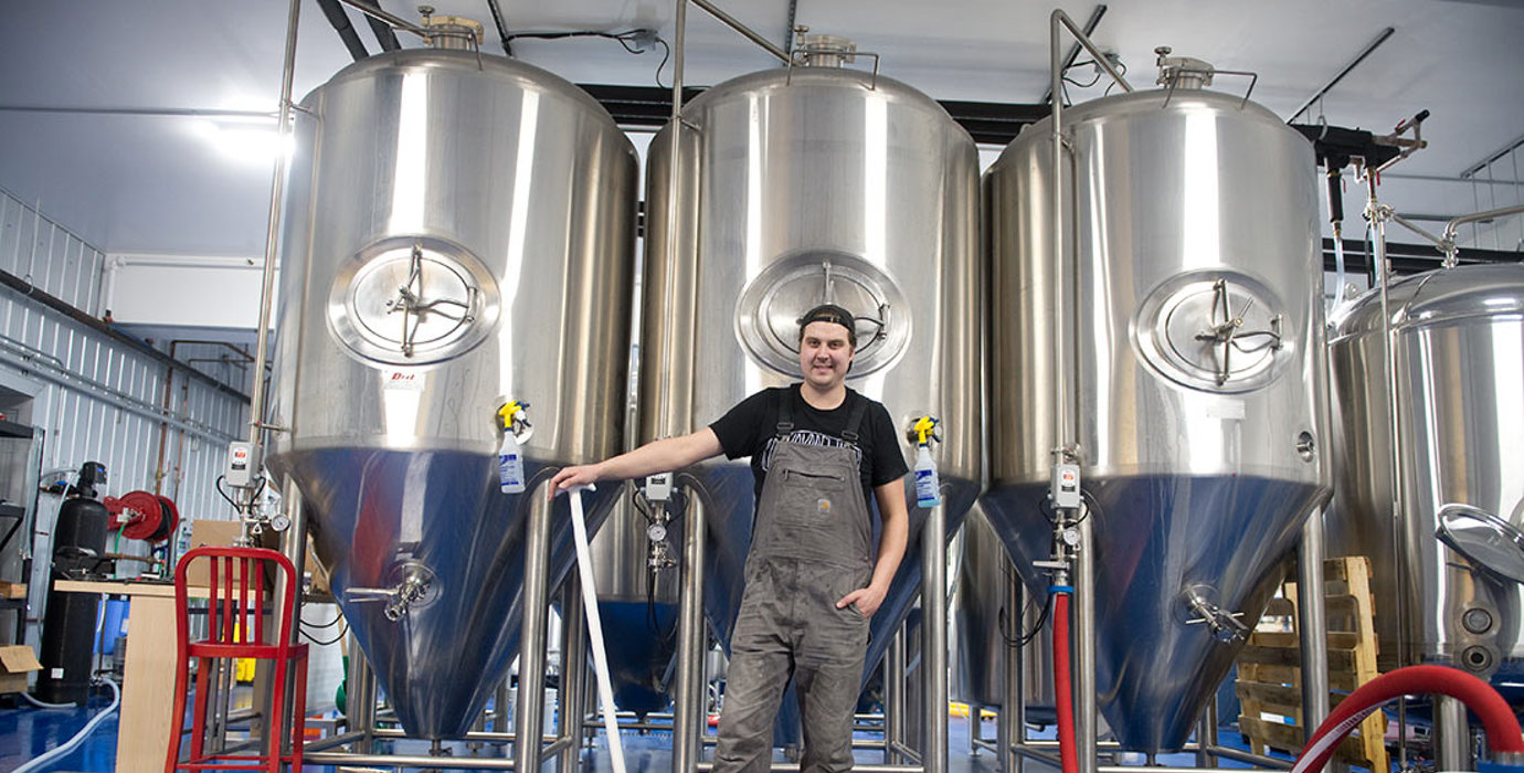 Entrepreneur in a brewer standing in front of fermenters