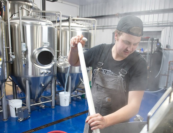 Entrepreneur in a brewery mixing ingredients in brewing tank