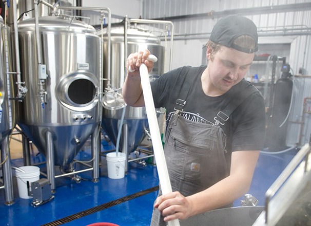 Entrepreneur in a brewery mixing ingredients in brewing tank