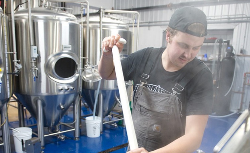 Entrepreneur in a brewery mixing ingredients in brewing tank