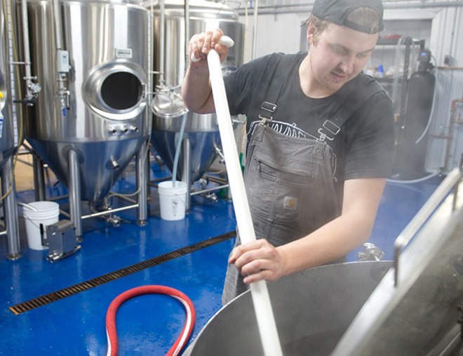 Entrepreneur in a brewery mixing ingredients in brewing tank