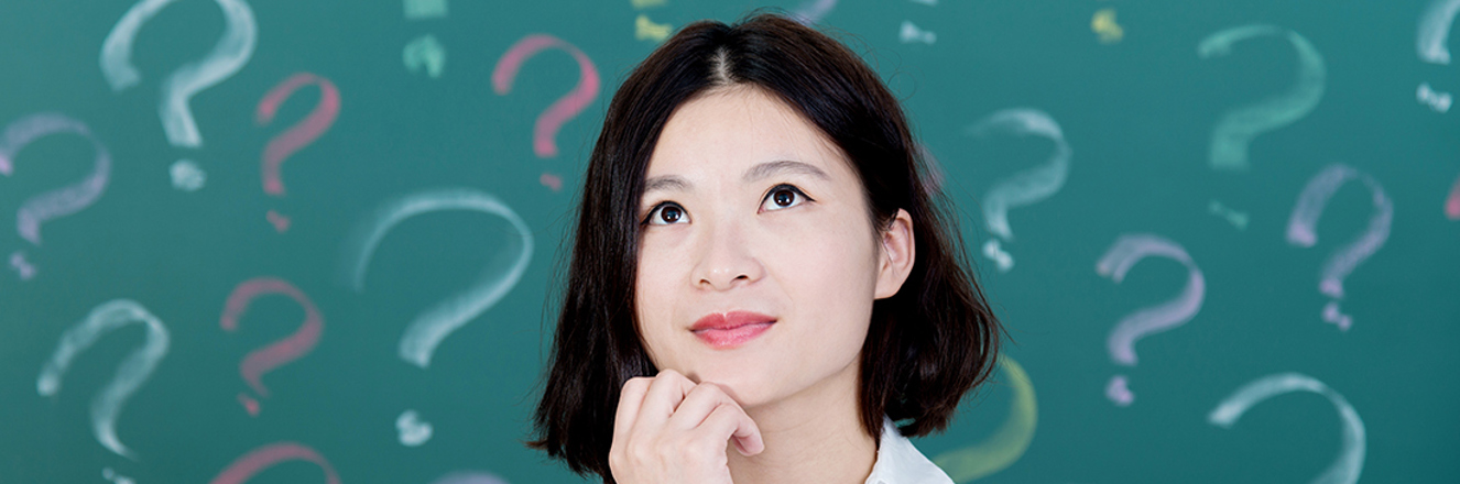 Person looking up with chin in hand in front of a background of question marks