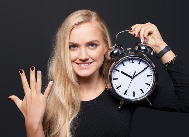 Person holding up 5 fingers and holding an alarm clock