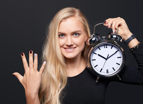 Person holding up 5 fingers and holding an alarm clock
