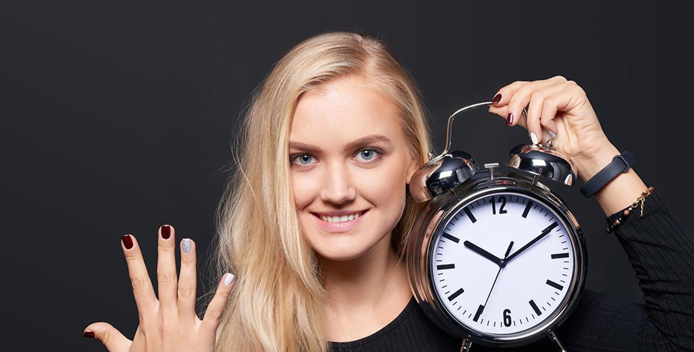 Person holding up 5 fingers and holding an alarm clock