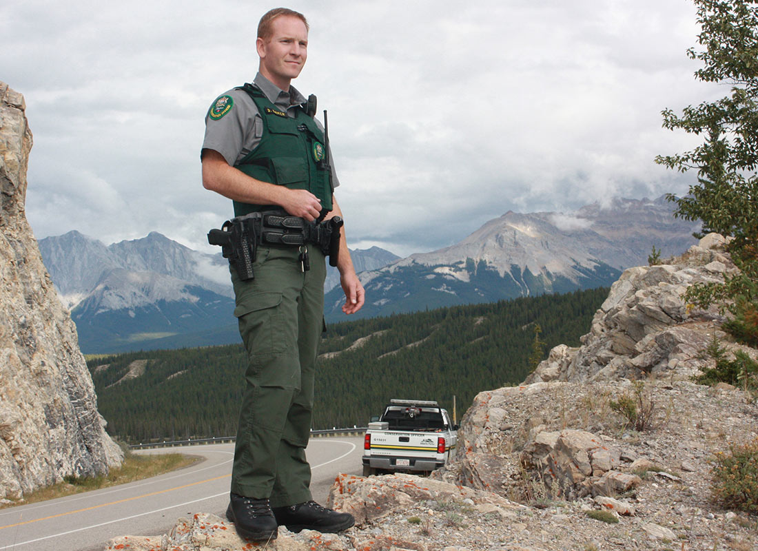 Conservation officer standing on a rock with mountains in the background