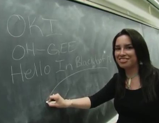 University student writing Blackfoot words on the blackboard