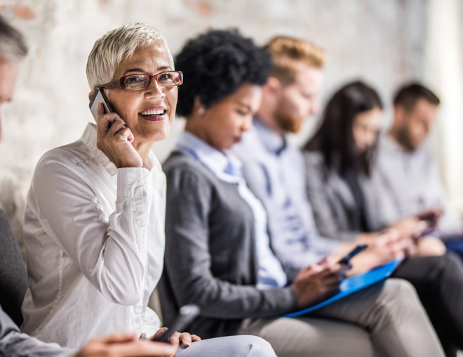 Person waiting in interview lineup talking on a smartphone