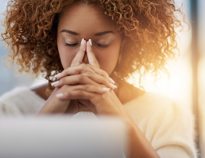 Person with eyes closed, fingers tented in front of face