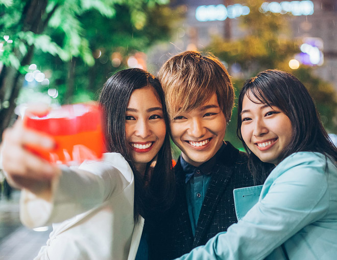 Friends taking a selfie on the sidewalk at night