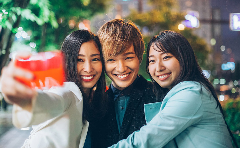 Friends taking a selfie on the sidewalk at night