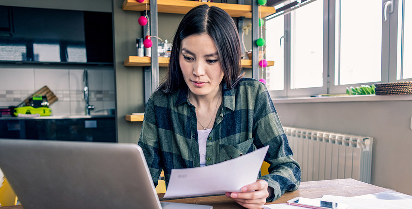 Person working at home with laptop and paper