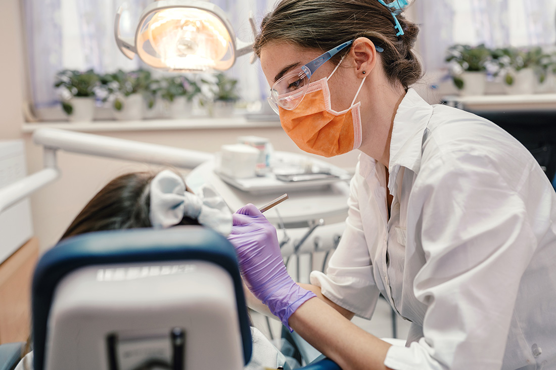 Dental hygienist working with a client in a dental chair