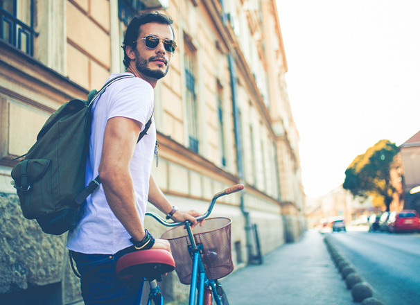 Student walking a bike on a city sidewalk