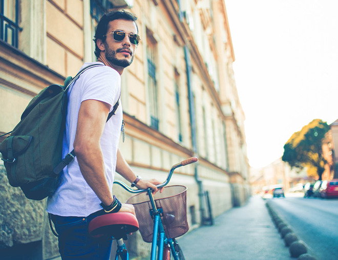 Student walking a bike on a city sidewalk