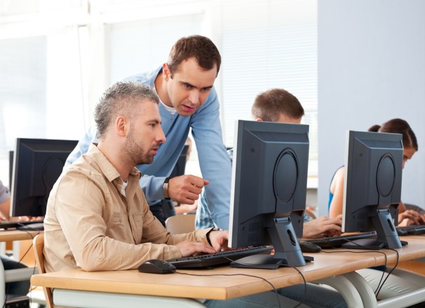 Mature student and teacher talking in a computer lab