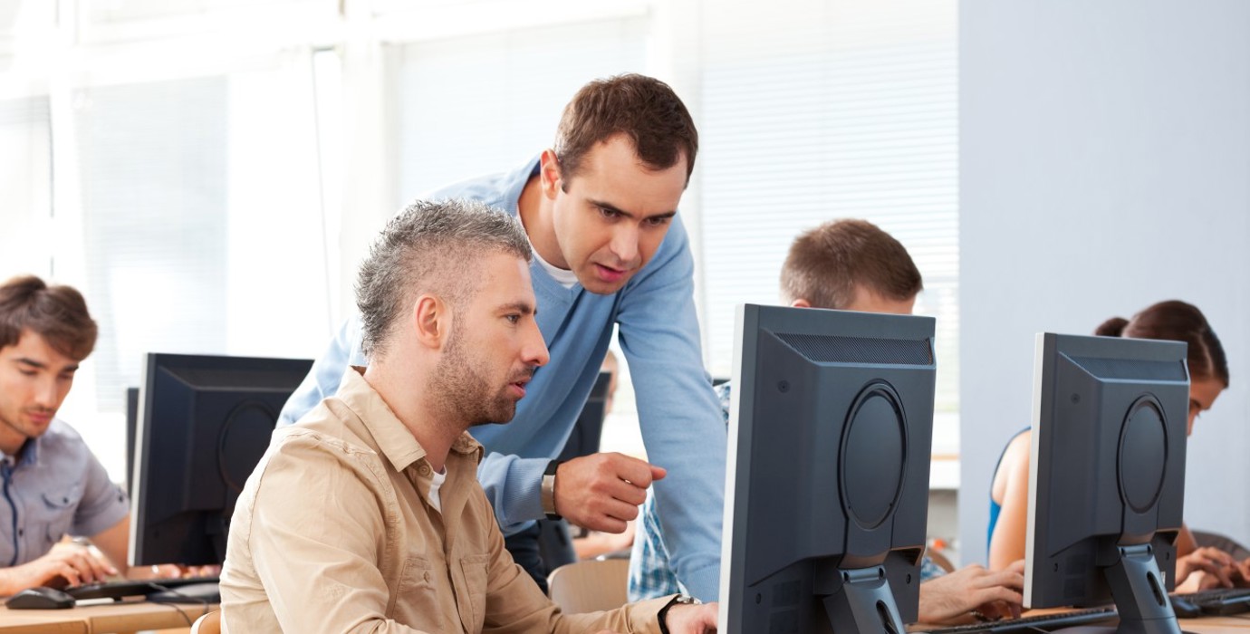 Mature student and teacher talking in a computer lab