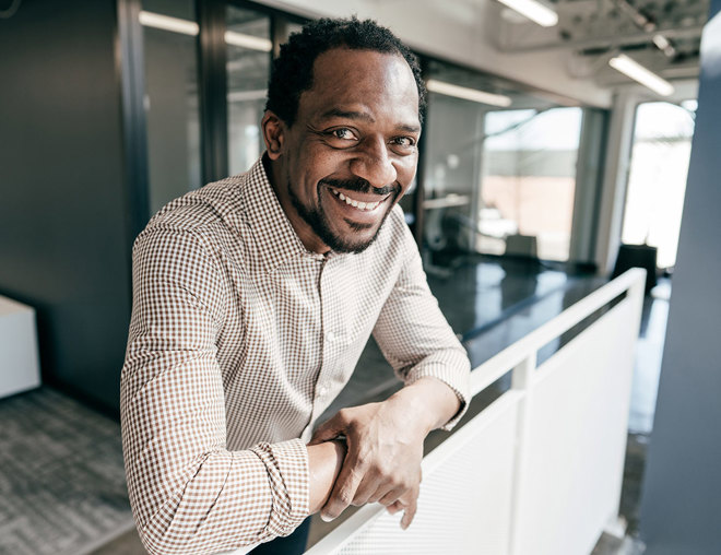 Person smiling into the camera leaning on a balcony railing