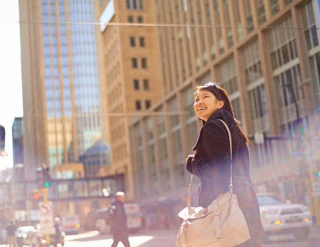 Person carrying a messenger bag and smiling while walking in a downtown area