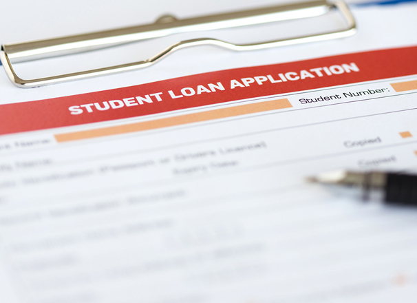 Paper application for student loan on a clipboard with a pen lying on top