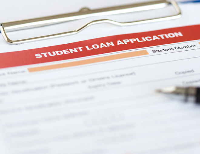 Paper application for student loan on a clipboard with a pen lying on top